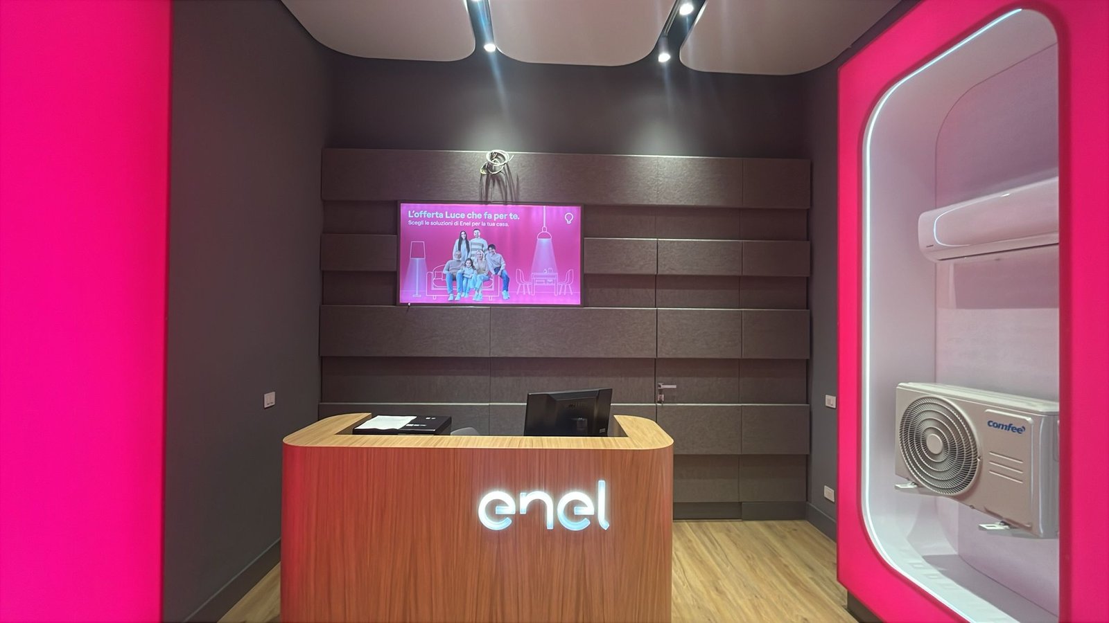 Facciata sera dello Spazio Enel Partner Portici Viale Leonardo da Vinci 141: insegna Enel colorata illuminata, vetrina con illuminazione magenta interna, edificio residenziale con balcone al piano superiore, lampione storico in stile napoletano, marciapiede in cubetti chiari, contesto residenziale collinare